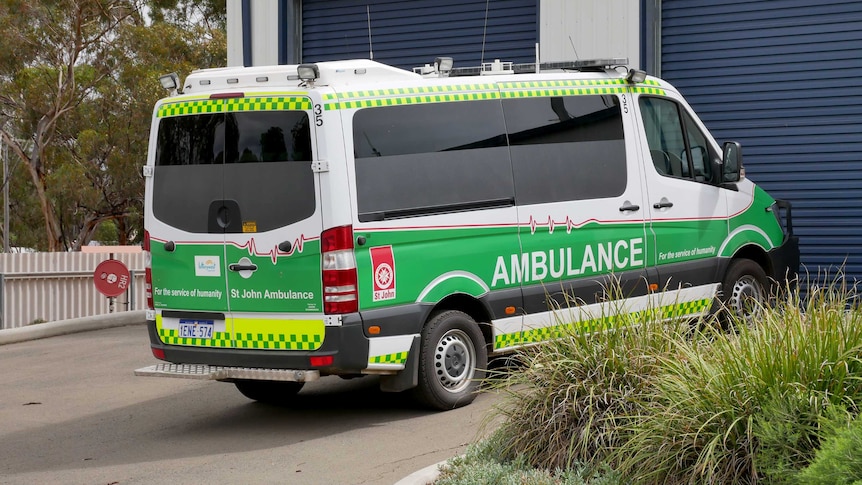 An ambulance parked outside a closed garage door.