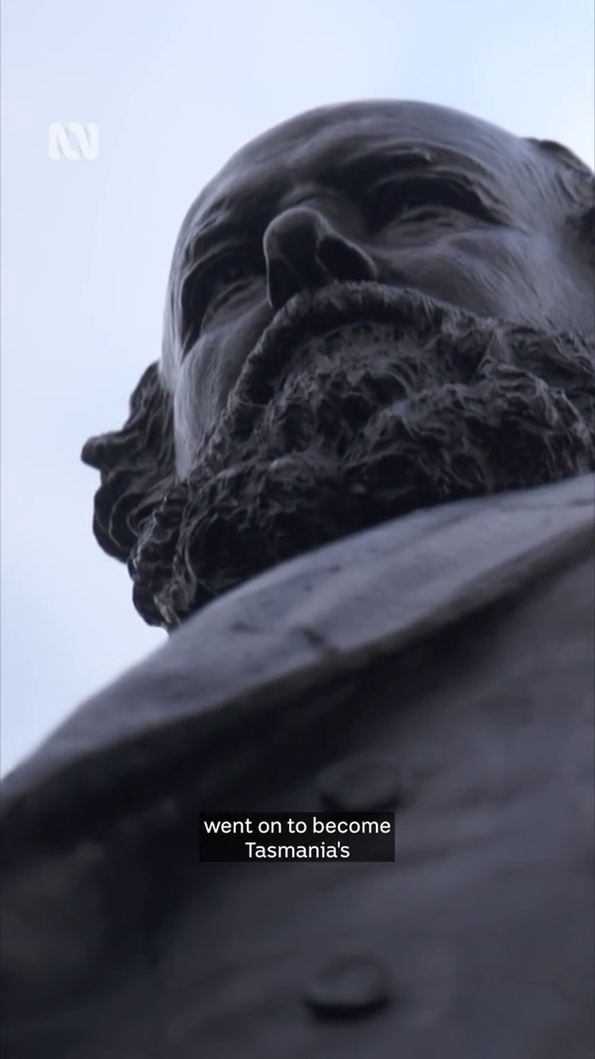 Looking up at a dark statue of a man with a large beard
