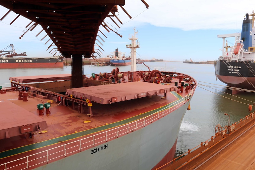 Iron ore drops from a conveyor belt into the hatch of a ship at the FMG port at Port Hedland.