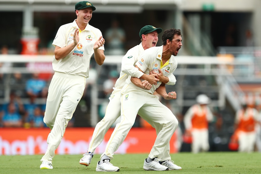 Mitchell Starc is hugged by Marnus Labuschagne after a wicket on the first ball of the Ashes. Cameron Green is behind, clapping.