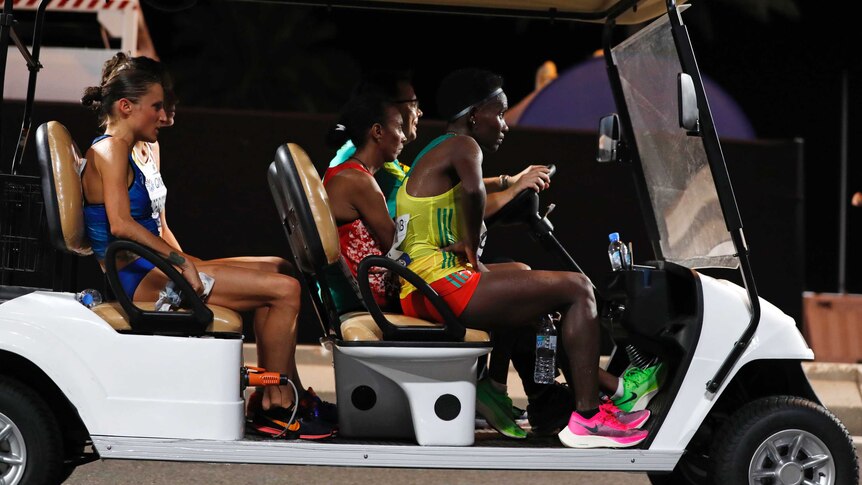 A group of female runners sit in a golf cart being driven away after abandoning a marathon.