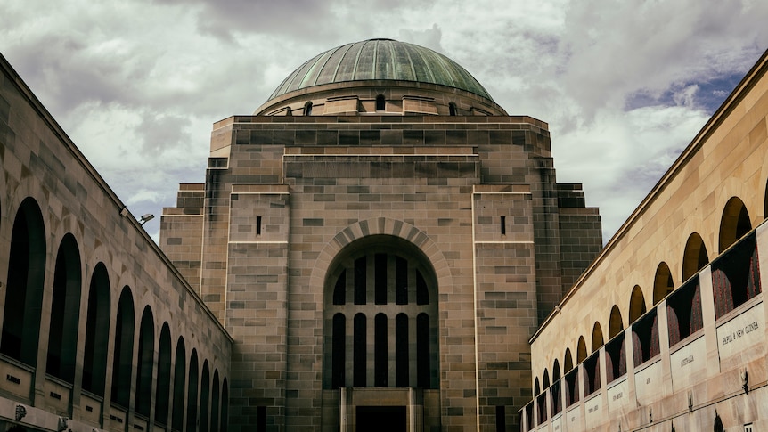 A grand sandstone dome with arches on either side, under a cloudy sky