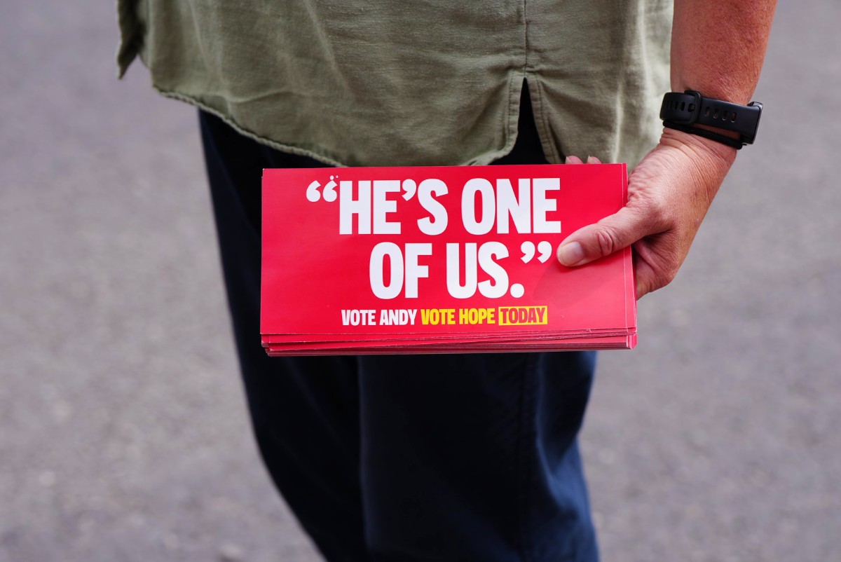 A woman's hand holding a stack of papers which say He's One of Us on them.