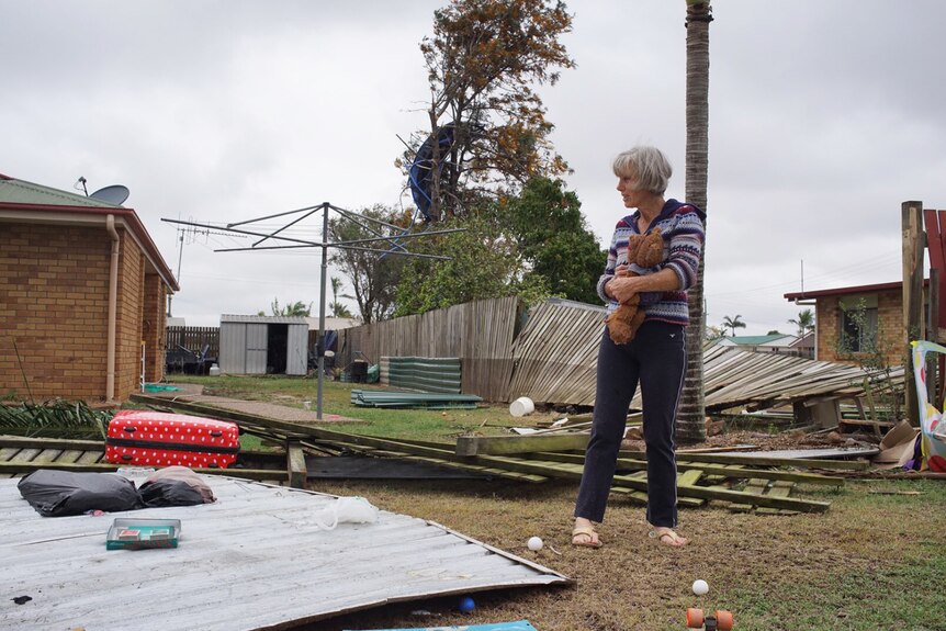 A resident looks at damage in Bundaberg on October 3, 2017, with a trampoline in a tree in the background