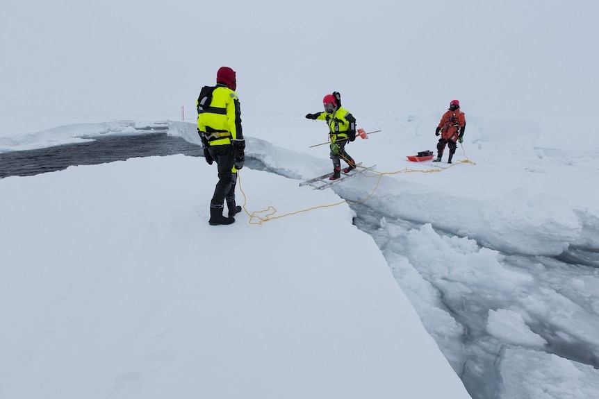 Arctic expedition members crossing an open lead