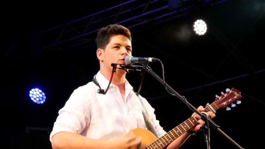Blake O'Connor on stage playing guitar and singing