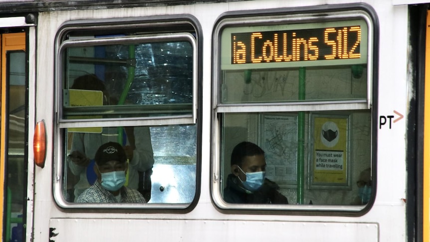 两名戴着口罩的人坐在电车里。