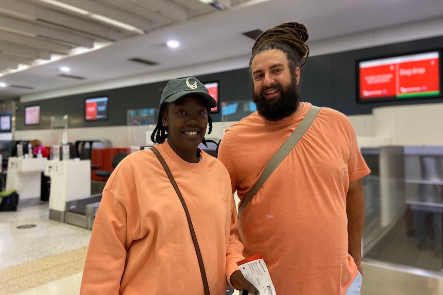 A woman and a man wearing orange at an airport