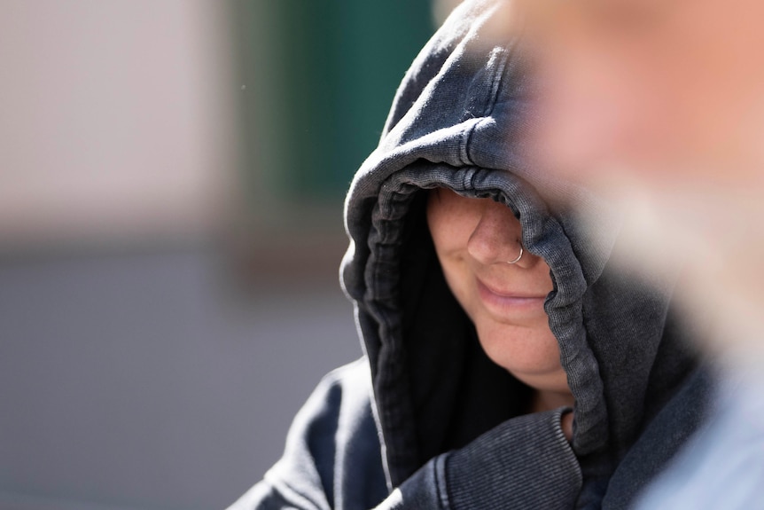 Emma Weitnauer covers her face in a hoodie.