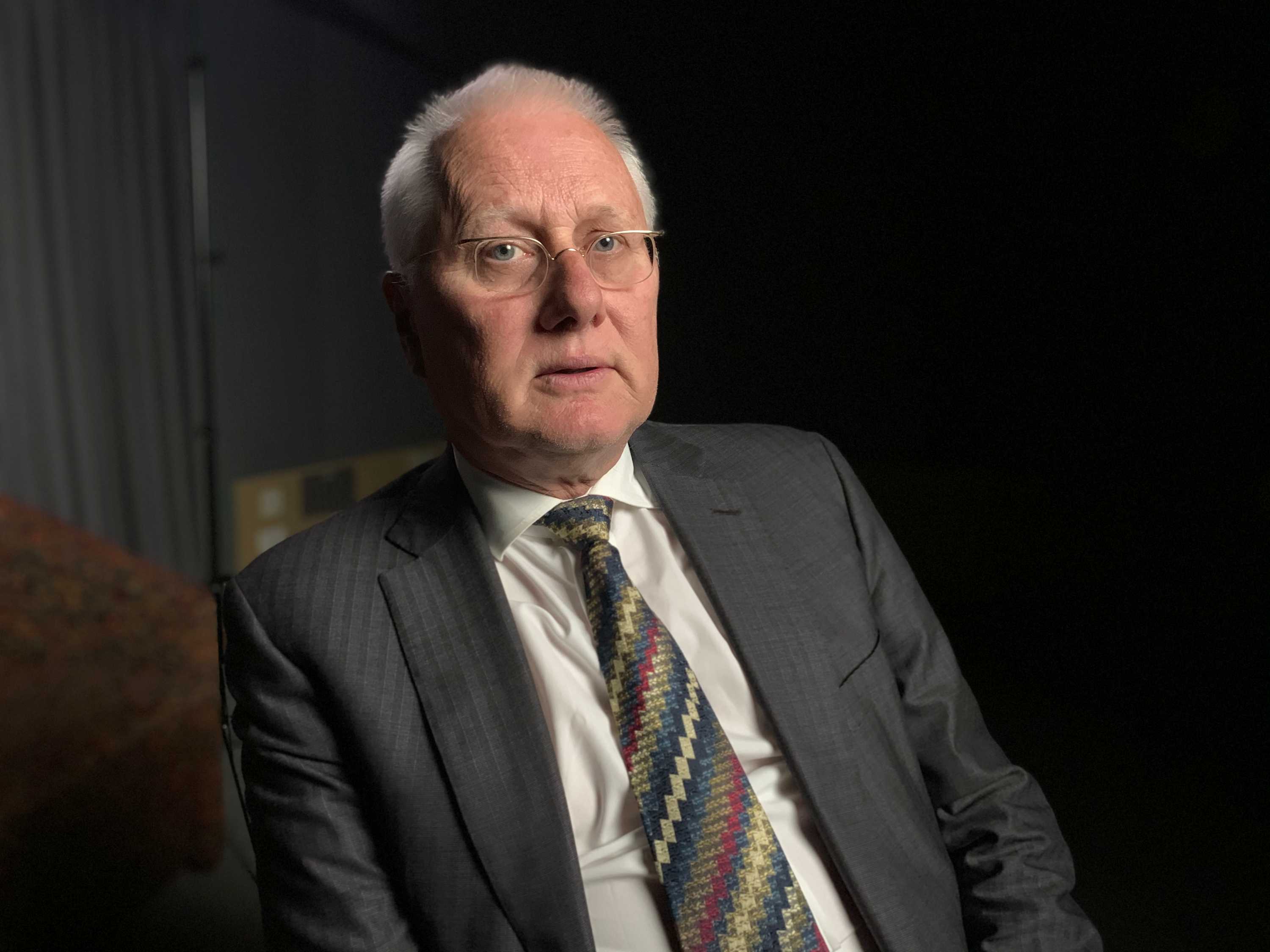 Brett Walker SC looks at the camera, wearing a charcoal suit and coloured tie.