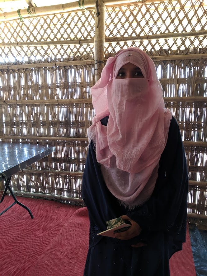Agitda wearing a pink niqab and standing inside a hut.