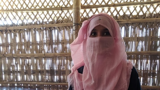 Agitda wearing a pink niqab and standing inside a hut.