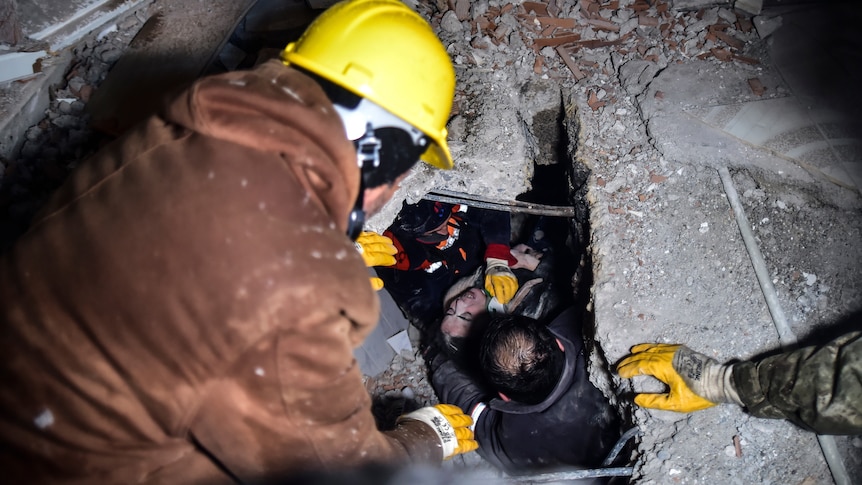 Emergency workers and medics rescue a woman out of the debris of a collapsed building.