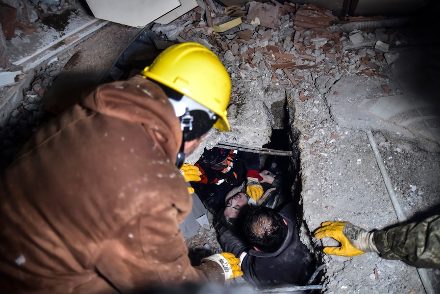 Emergency workers and medics rescue a woman out of the debris of a collapsed building.