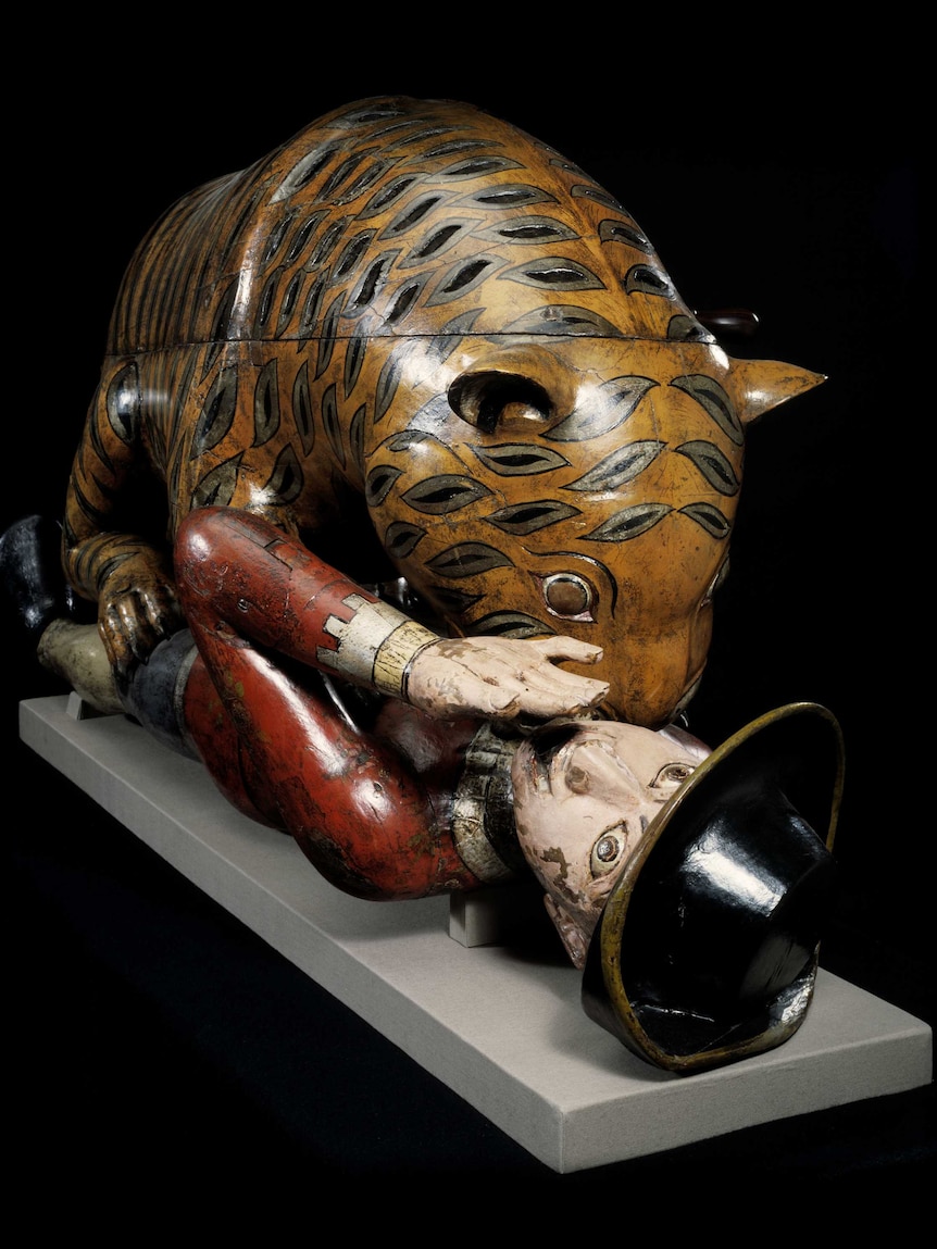 A wooden automaton of a tiger mauling a British soldier. The soldier's eyes stare and he is raising a hand.