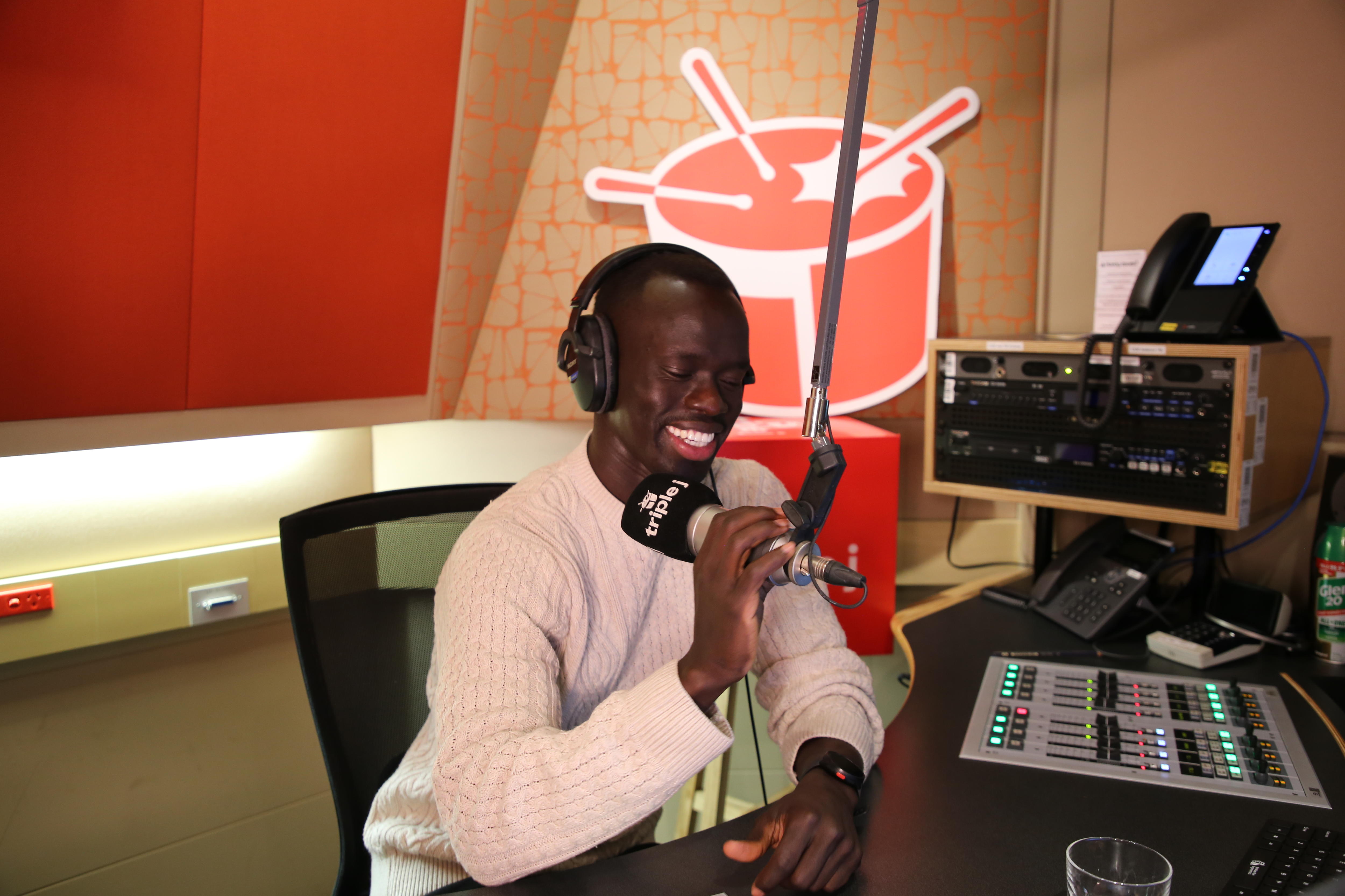 Socceroos star Awer Mabil speaks into a microphone in a studio