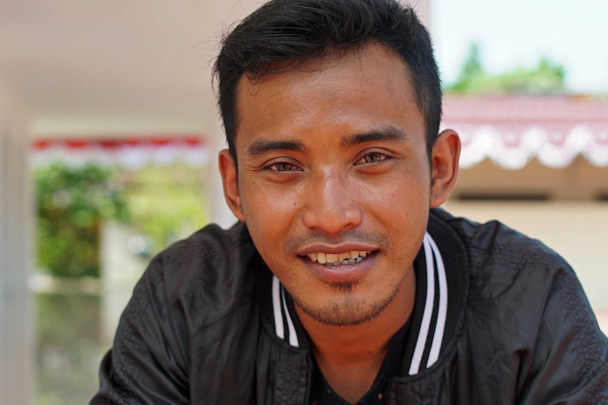 Ali Fauzi smiles looking into the camera in a close up photo of his face. He is sitting at the Peace Circle compound.