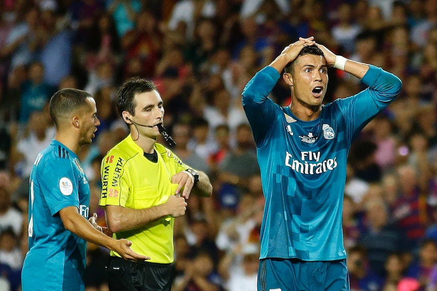 Real Madrid's Cristiano Ronaldo (R), reacts after he is shown a yellow card against Barcelona.