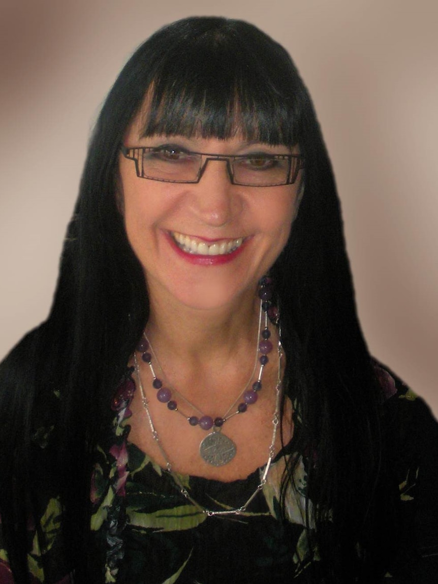 Head shot of Helen Grasswil with long black hair and wearing glasses smiling to camera.