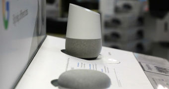 A Google Home and Google Home Mini device on a display stand in a shop with price tags on the side.
