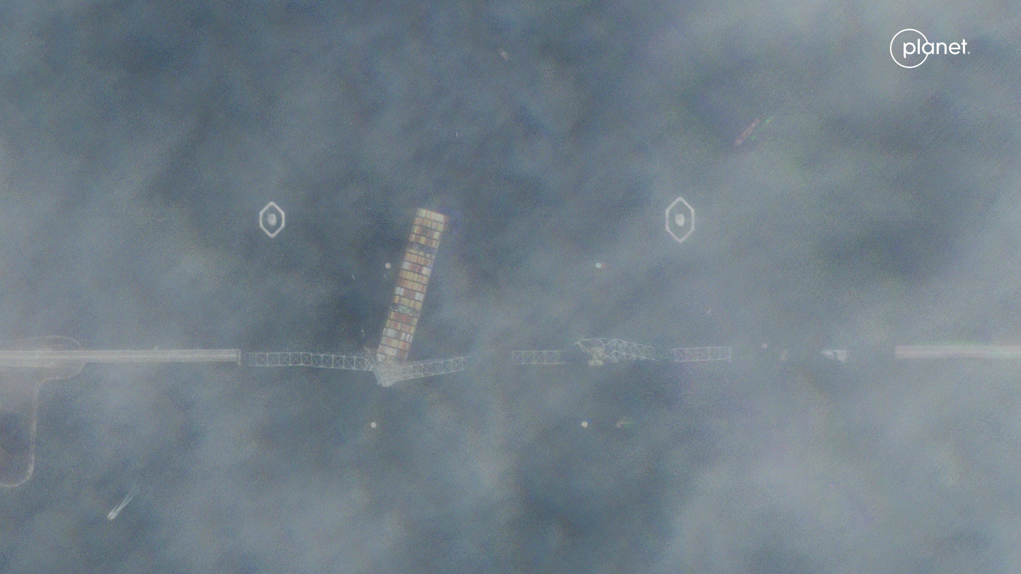 A blury sattelite image of a ship under a destroyed bridge
