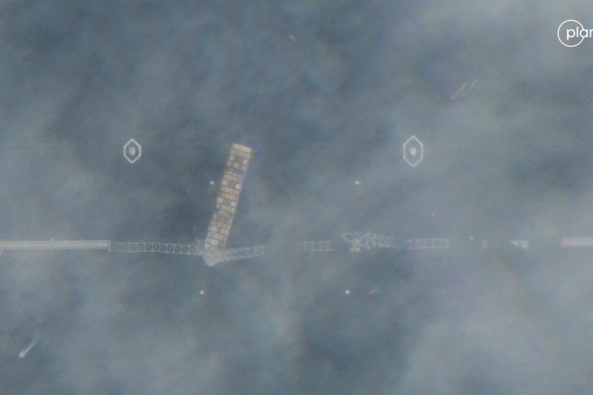 A blury sattelite image of a ship under a destroyed bridge