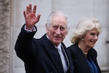 King Charles waves as he walks alongside Queen Camilla 
