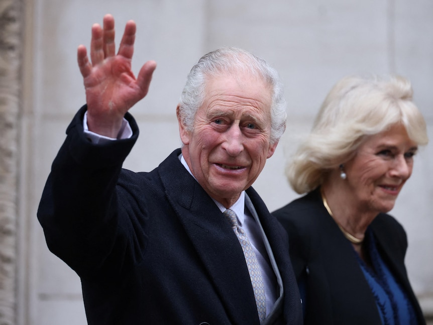 King Charles waves as he walks alongside Queen Camilla 