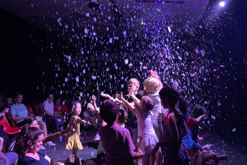 Delighted children in a dark theatre as fake snow falls from the ceiling