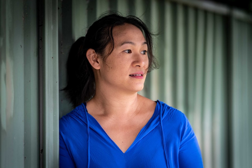 Emily Yu stands in front of a corrugated iron fence and looks out into the distance.