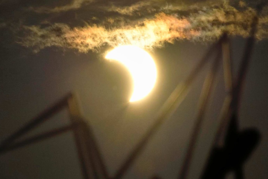 A partial solar eclipse is seen over the Children's Peace Monument at Hiroshima Peace Memorial Park.