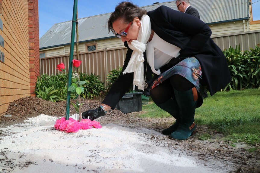 Cemetery Manager Annie Dejon lays a flower at the site where 16 unclaimed cremated remains have been laid to rest in Ballarat.