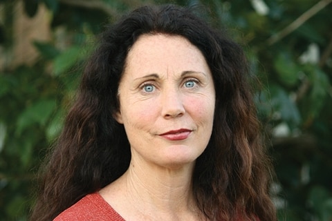 Head shot of a woman with long, brown hair, wearing a red top
