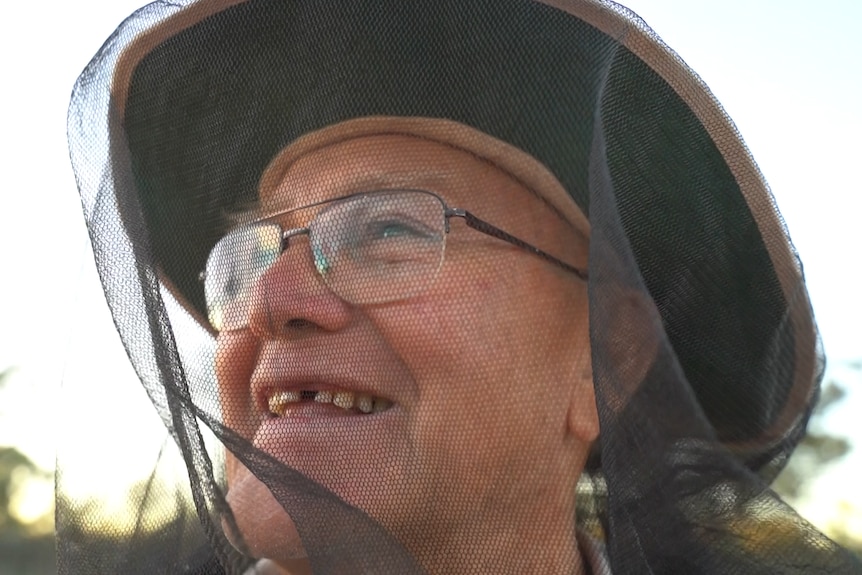Man wearing bee net and glasses looking out at sky