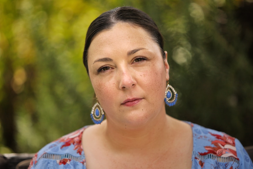 Woman wearing a blue top sitting outside.