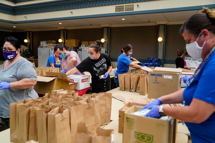People work together to pack lunches at an evacuation center