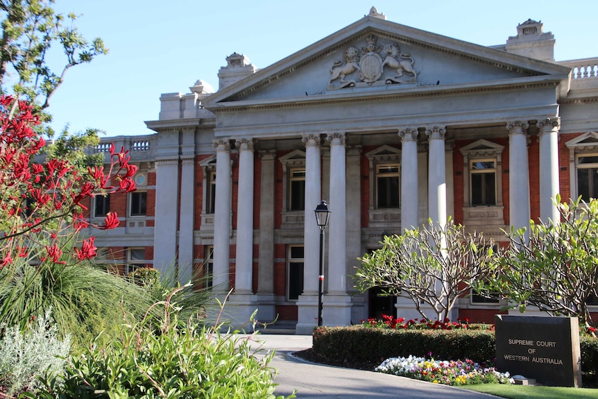 Exterior shot of the WA Supreme Court building in Perth with red kangaroo paws in the foreground at left.
