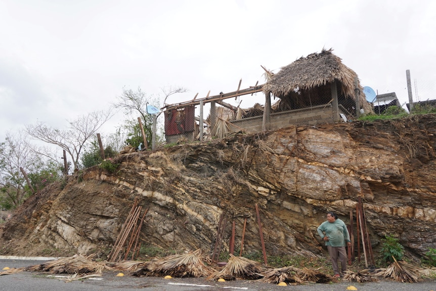 Una casa con techo de paja destruida cerca de un deslizamiento de tierra