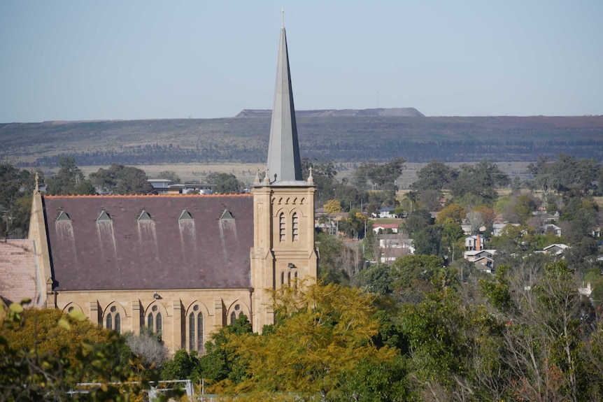 Scenic photo of town showing church, houses and surrounding farmland.