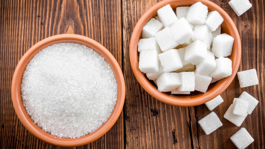 Two bowls of sugar, one containing sugar cubes and the other granulated sugar