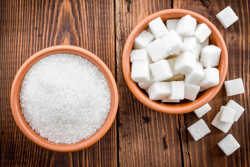Two bowls of sugar, one containing sugar cubes and the other with castor sugar.