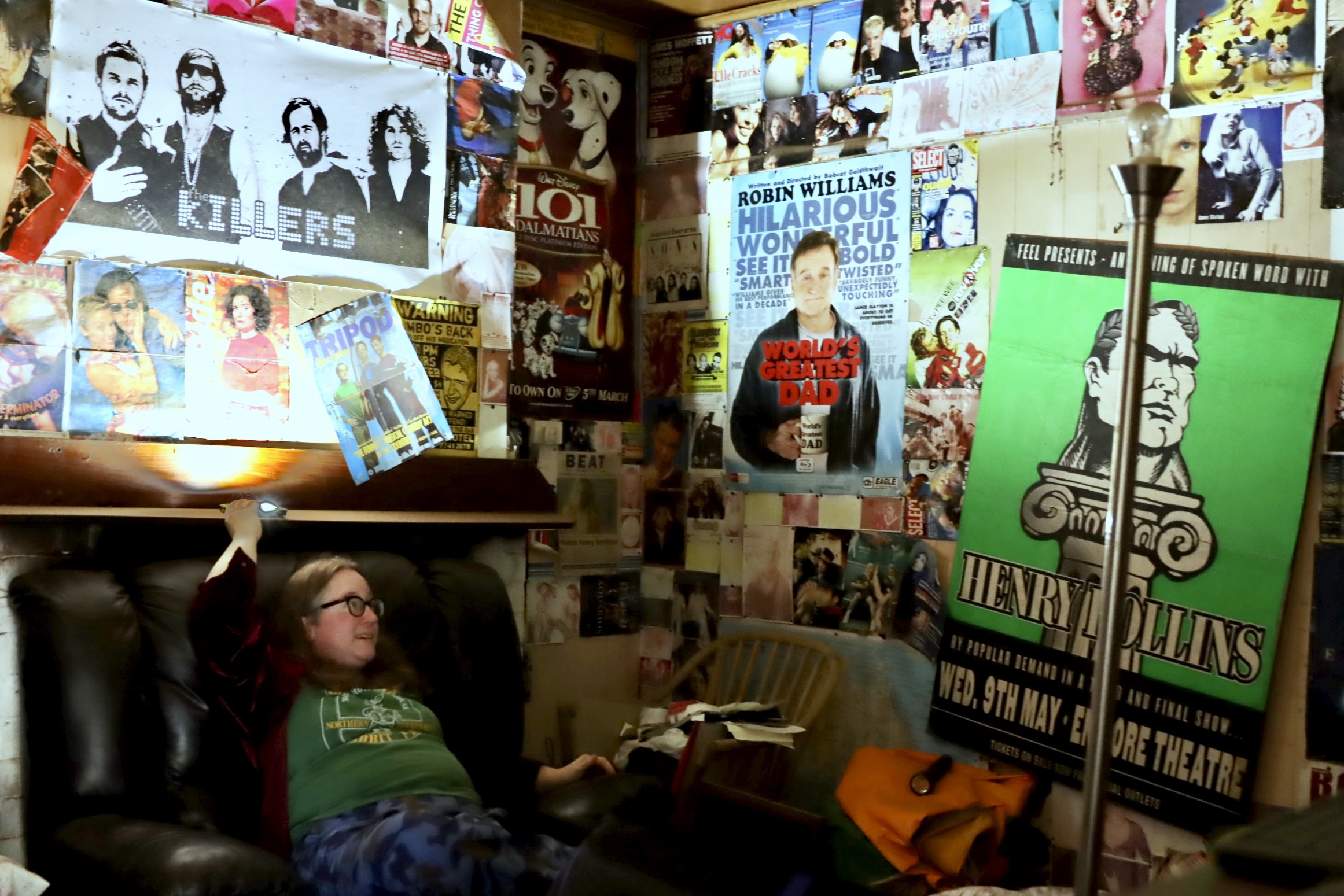 woman in a room with walls plastered with posters 