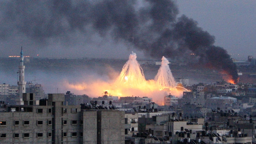 A skyline view of Gaza showing two white phosphorus bombs exploding in the distance.
