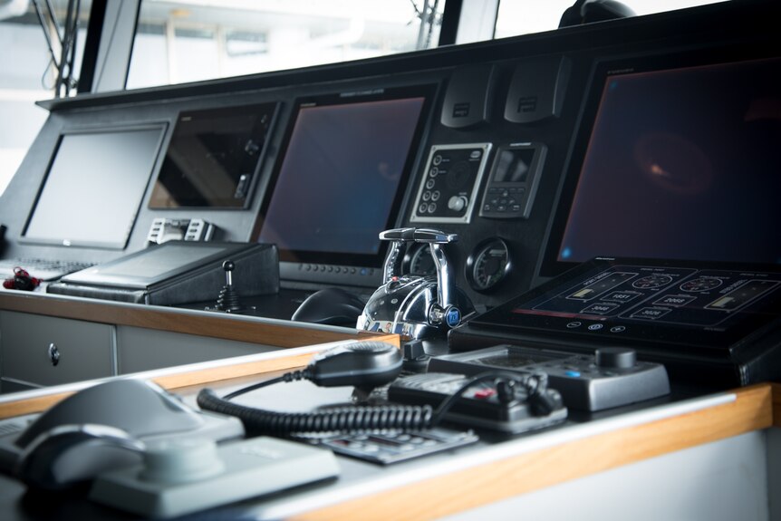 The video screens, throttle levers and other controls of a ship's wheelhouse.