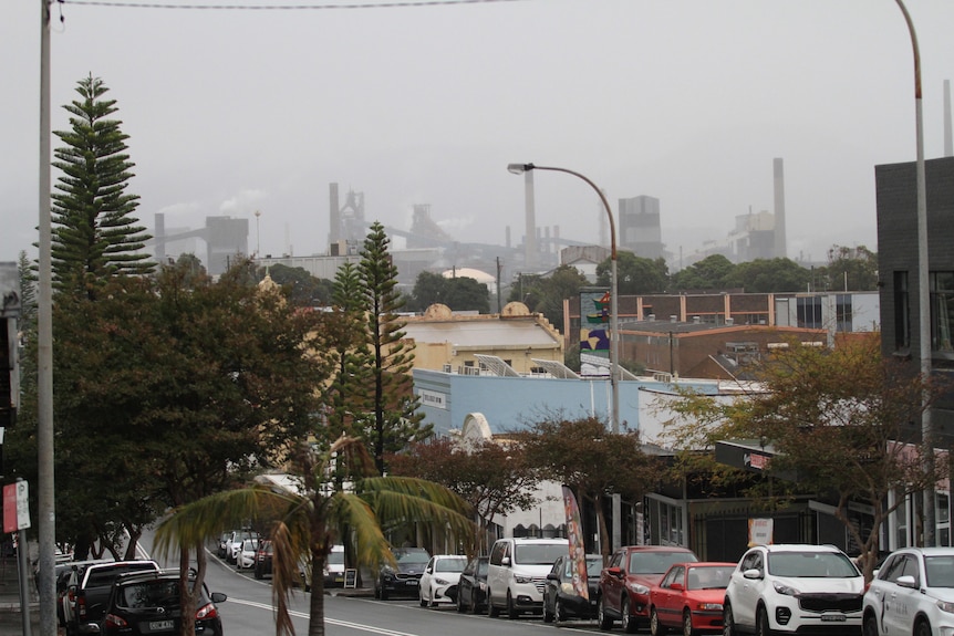 Tall chimneys can be seen in the distance, while a suburban street is in the foreground.