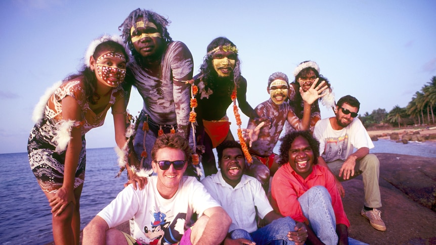 a band of mostly aboriginal musicians smiling at the beach