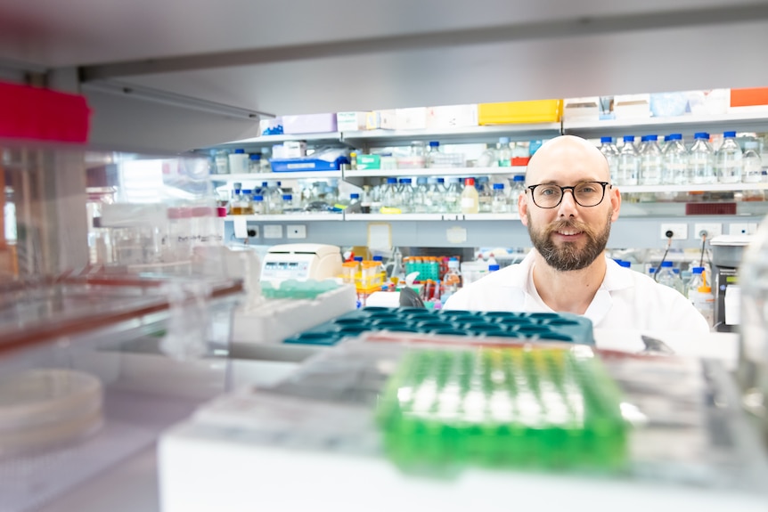 Young man in a university science lab with lots of bottles and chemicals around him