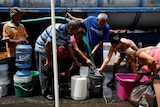 eople queue to fill containers with water from a tank truck at an area hit by Hurricane Maria