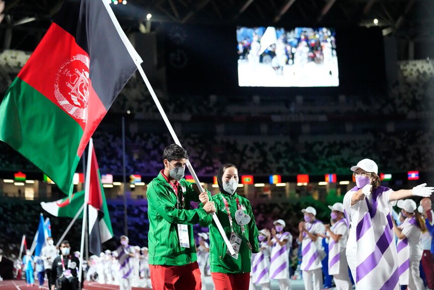 Two Afghan athletes carry the national flag in the Olympic Stadium during the Tokyo Paralympics closing ceremony.