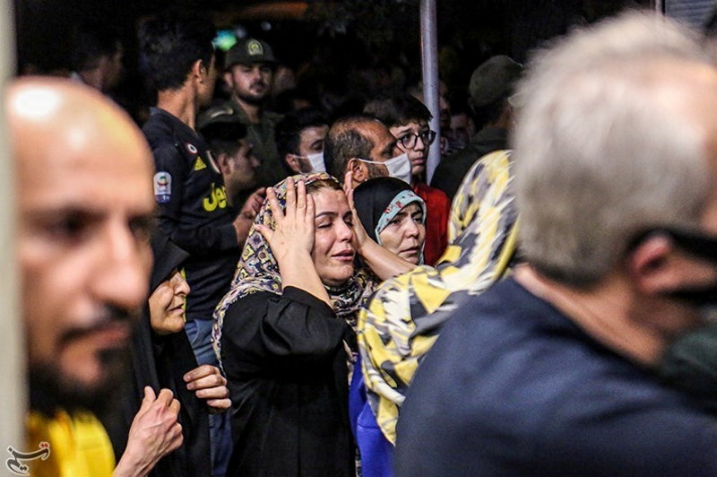 A woman wearing a hijab clutches her face in a crowd